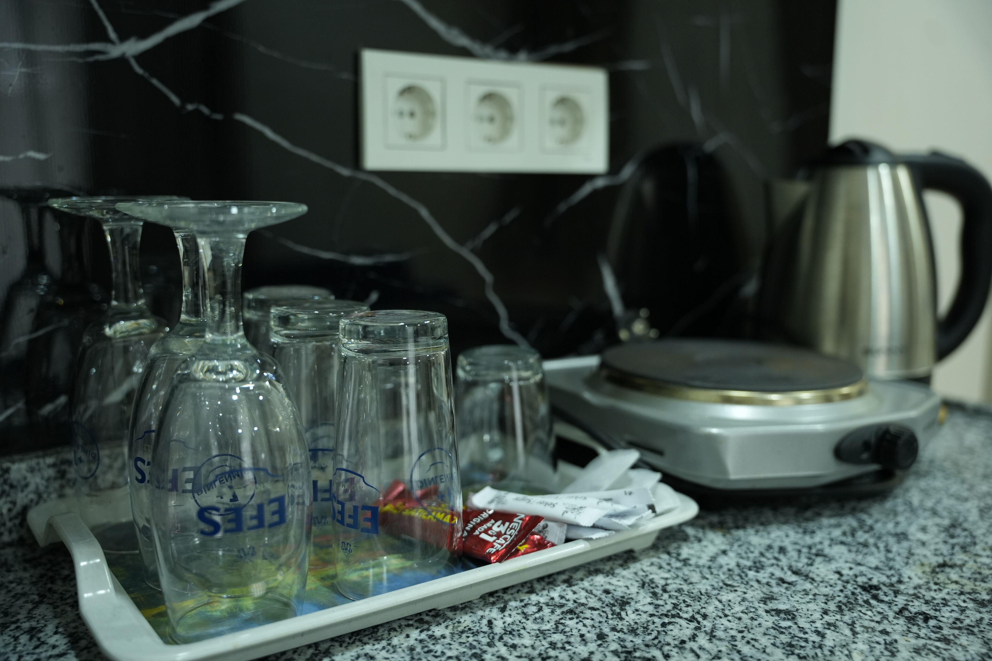 Eine Küchenarbeitsplatte mit Weingläsern, einem Wasserkocher und einer Platte mit Snacks.