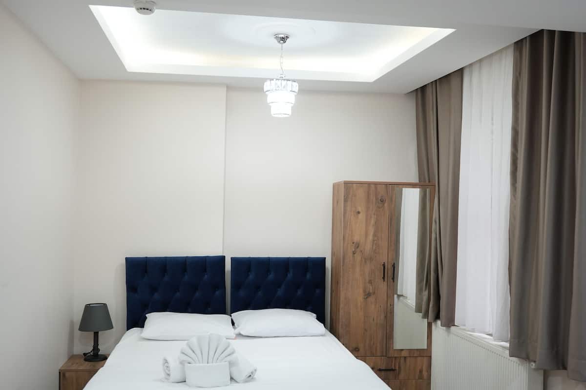 A bedroom with a bed, a wardrobe, a nightstand, a lamp, and a ceiling light.