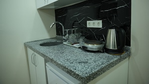 Une cuisine dotée d’un plan de travail en granit, d’un pare-feu en marbre noir et blanc, d’une bouilloire en acier inoxydable et d’une machine à café.
