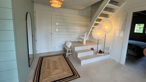 A modern interior with a staircase, a chandelier, and a bench. - Chalet bois cœur Cévennes (Saint-Sauveur-Camprieu)