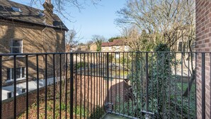 A residential area with brick houses, a metal fence, and leafless trees.