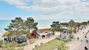 A coastal area with a paved walkway, beachside buildings, and a view of the sea. - Residence Ostseestrand Apartment 31 "Aurora" - Residence Ostseestrand (Scharbeutz)