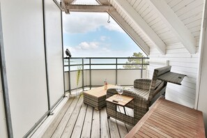 A balcony with wicker furniture, a table, and a bottle.
