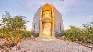 A modern building with a unique architectural design, featuring a central circular window and a balcony with a railing. - The Ekipa (Okaukuejo)