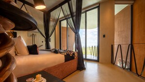 A modern hotel room with a large bed, a small table with candles, and a view of the outdoors. - The Ekipa (Okaukuejo)