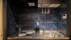 Une cuisine moderne dotée d’un plan de travail en acier inoxydable, d’un évier à deux bacs et d’une machine à café.