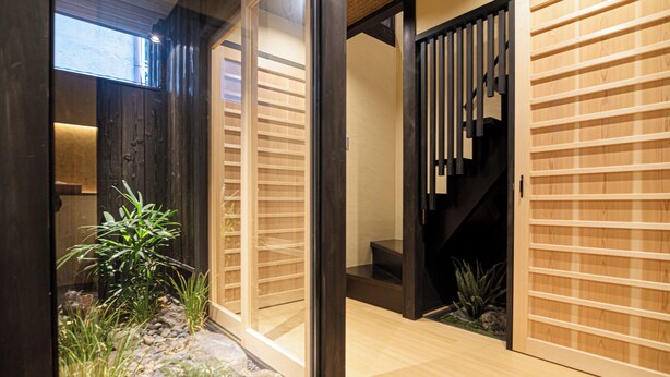 Un intérieur moderne avec un plancher en bois, un escalier et un petit jardin intérieur agrémenté de rochers et de plantes.