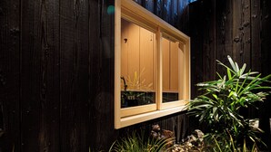 Une façade en bois, une fenêtre et un petit jardin agrémenté de rochers et de plantes.
