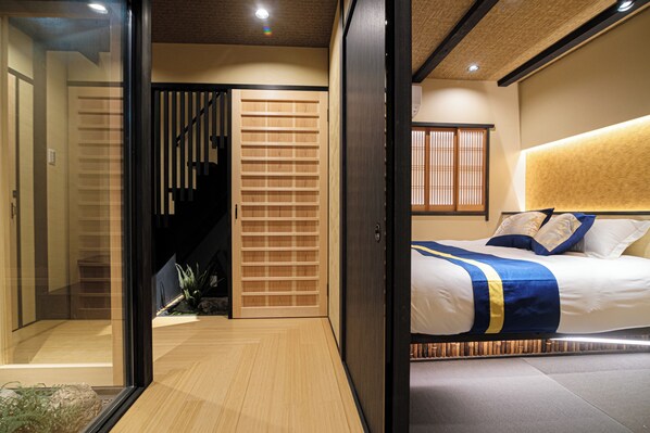 A modern hotel room with a large bed, a sliding door, and a staircase.
