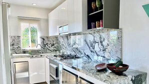 A modern kitchen with white cabinetry, a marble countertop, and a built-in oven. - by Calamari Homes - Edificio Centenario (Cartagena)