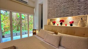 A bedroom with a large bed, a wooden headboard, and a brick wall. - by Calamari Homes - Edificio Centenario (Cartagena)