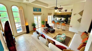 A spacious living area with a large sofa, a dining table, and a kitchen in the background. - by Calamari Homes - Edificio Centenario (Cartagena)