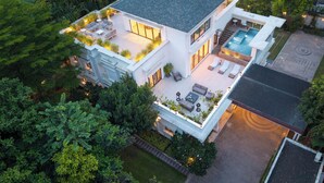 Ett modernt hus i två våningar med en takterrass, en swimmingpool och en välskött trädgård.