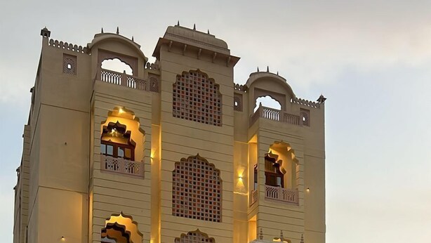 Un edificio ampio e decorato, con numerosi balconi e finestre ad arco, caratterizzato da un'ampia corte interna con pavimento piastrellato.