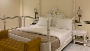 Un letto a baldacchino con testiera bianca, un comodino con una lampada e una poltrona gialla.