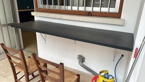 Un comptoir de cuisine avec une fenêtre au-dessus, une chaise et une bouteille de gaz jaune.
