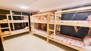 Une chambre avec des lits superposés, un plancher en bois et une fenêtre.