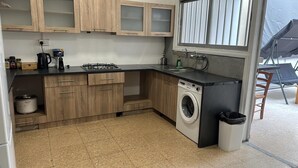 Une cuisine de taille réduite, dotée de meubles en bois, d’une cuisinière à gaz, d’un lave-linge et d’un évier.