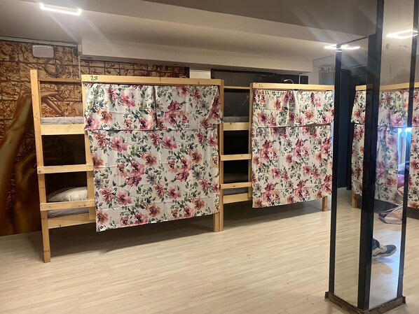 Une chambre avec des lits superposés, des têtes de lit en bois et des rideaux à motifs floraux.