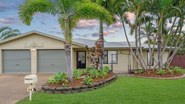 A single-story house with a garage, a mailbox, and a well-maintained lawn with palm trees.