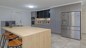 A modern kitchen with a central island, bar stools, a microwave, oven, and stainless steel appliances.