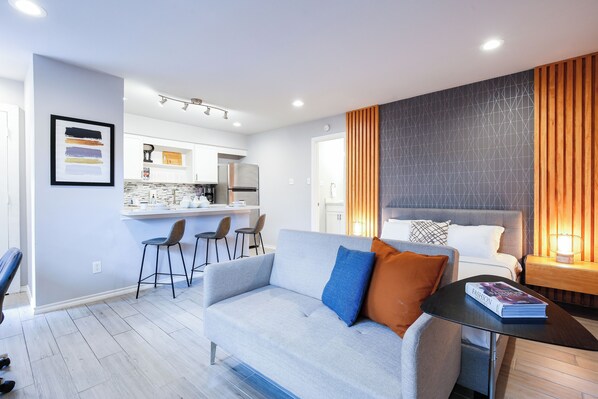 A modern living room with a sofa, a coffee table, and a dining area with chairs.