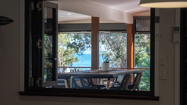 Ein Essbereich mit Tisch und Stühlen, Blick auf das Meer und ein großes Fenster.