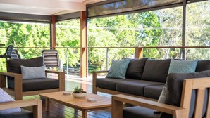 Ein moderner Außenbereich mit Holztisch, gepolsterten Stühlen und einer Couch.