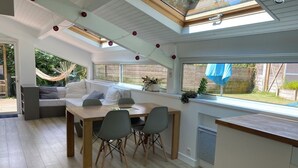 A modern kitchen with a dining area, large windows, and a view of the garden. - Villa 71 Hossegor with heated pool, basketball, pétanque and vacation atmosphere (Soorts-Hossegor)