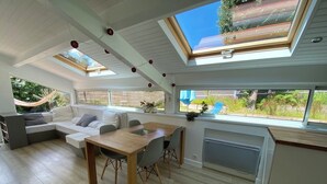 A modern interior with a dining area, sofa, and skylight. - Villa 71 Hossegor with heated pool, basketball, pétanque and vacation atmosphere (Soorts-Hossegor)