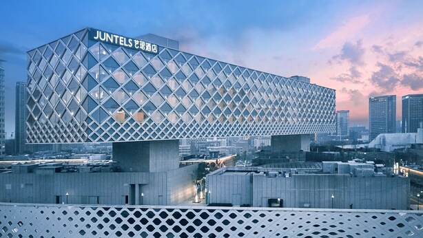 A modern hotel with a distinctive diamond-patterned facade and a prominent sign. - Hangzhou Binjiang Baolong Juntels (Hangzhou)