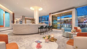 A modern lobby with a marble reception desk, seating area, and large windows offering a city view. - Hangzhou Binjiang Baolong Juntels (Hangzhou)