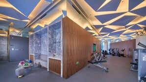 A modern gym with exercise equipment, a reception area, and a marble wall. - Hangzhou Binjiang Baolong Juntels (Hangzhou)