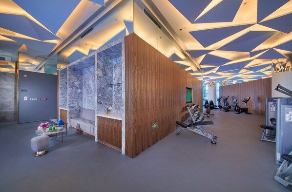 A modern gym with exercise equipment, a reception area, and a marble wall. - Hangzhou Binjiang Baolong Juntels (Hangzhou)