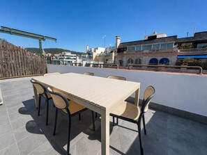 A rooftop terrace with a table and chairs, a wooden fence, and buildings in the background. - Stay U-nique Apartments Balmes II (Barcelona)
