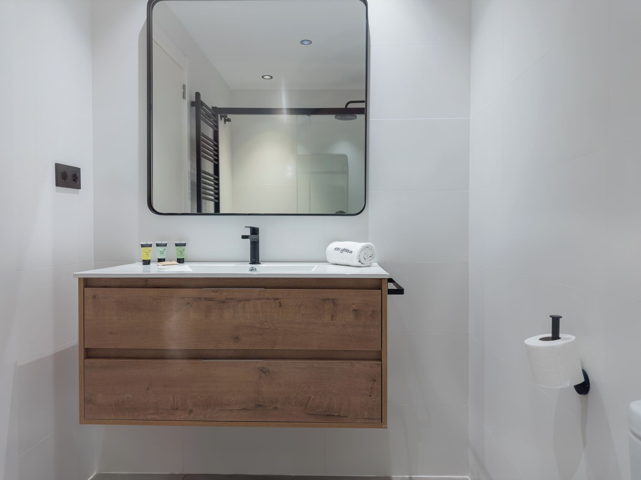 Une salle de bain moderne avec un meuble-lavabo en bois, un miroir et une serviette.