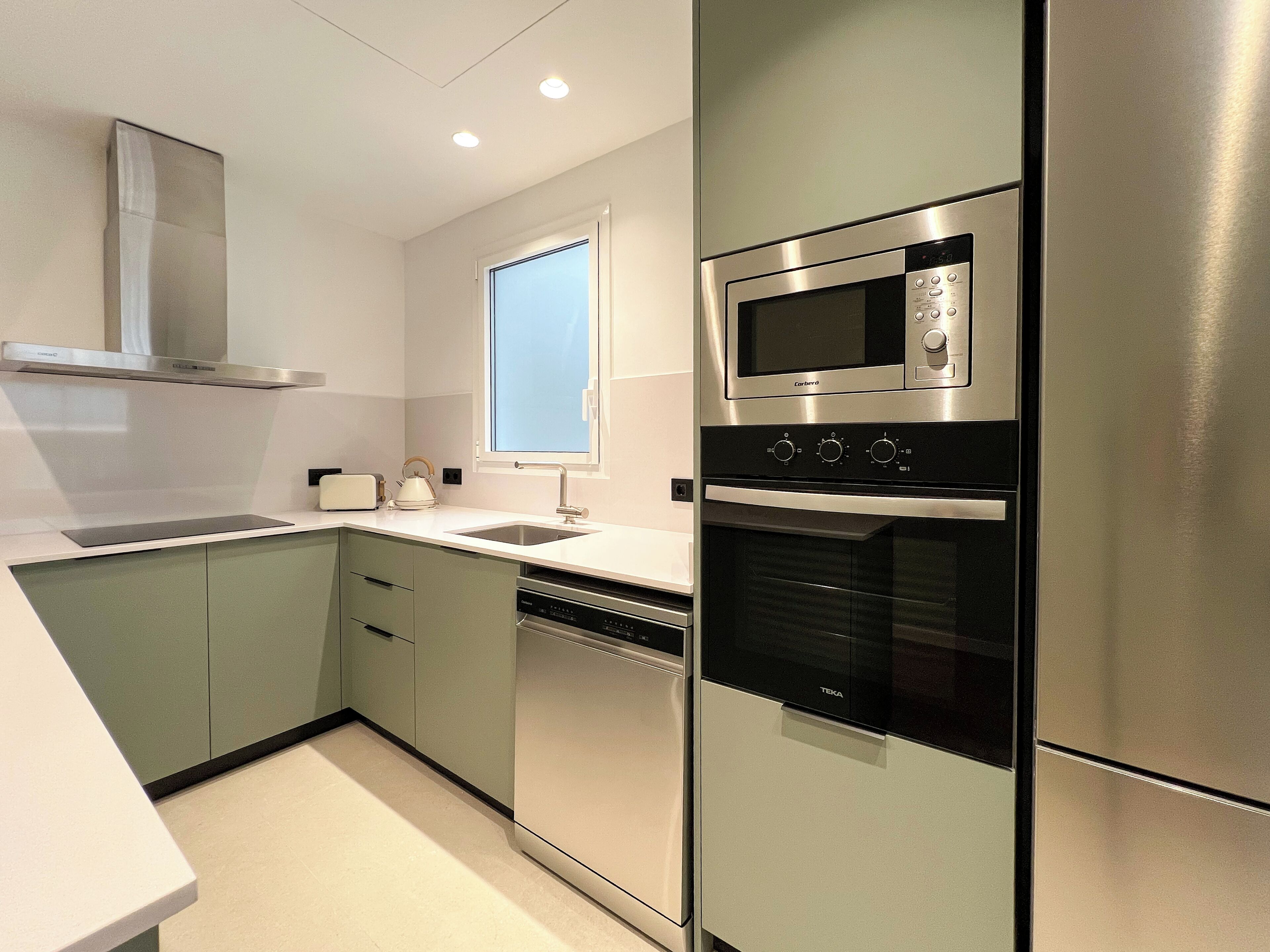Una cocina moderna con electrodomésticos de acero inoxidable, una ventana y un lavavajillas empotrado.