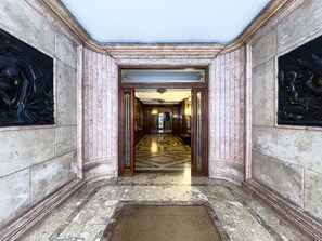 A grand hallway with marble walls and a polished floor, leading to a room with a large door. - Stay U-nique Apartments Balmes II (Barcelona)