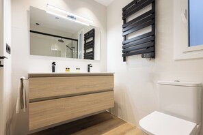 Un baño moderno con tocador de madera, inodoro y perchero de pared.