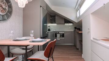 Una cocina moderna con comedor, que incluye una mesa de madera, sillas y un reloj en la pared.