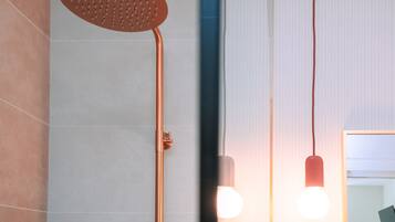 Un baño moderno con ducha, espejo e iluminación colgante.