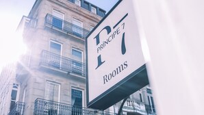 Un cartel que indica 'Príncipe 7 Rooms' con vista a un edificio con balcones y ventanas.