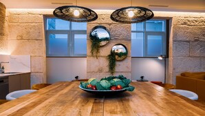 Una mesa de comedor de madera con un centro decorativo, paredes de piedra e iluminación moderna.