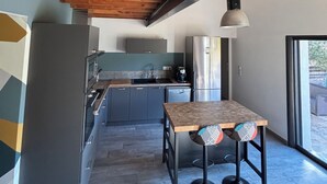 Una cocina moderna con techo de madera, armarios grises y un refrigerador de acero inoxidable.