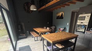 Cocina moderna con mesas y bancos de madera, un ventanal y vistas al exterior.