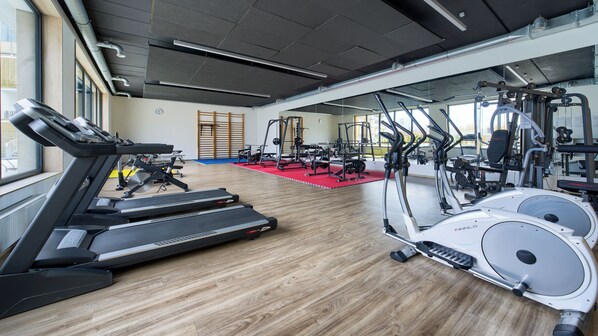 A gym with treadmills, elliptical machines, and weight equipment.