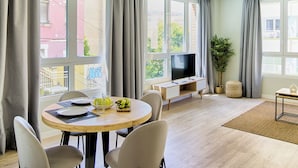 Ein modernes Wohnzimmer mit Essbereich, großen Fenstern und einem Flachbildfernseher.