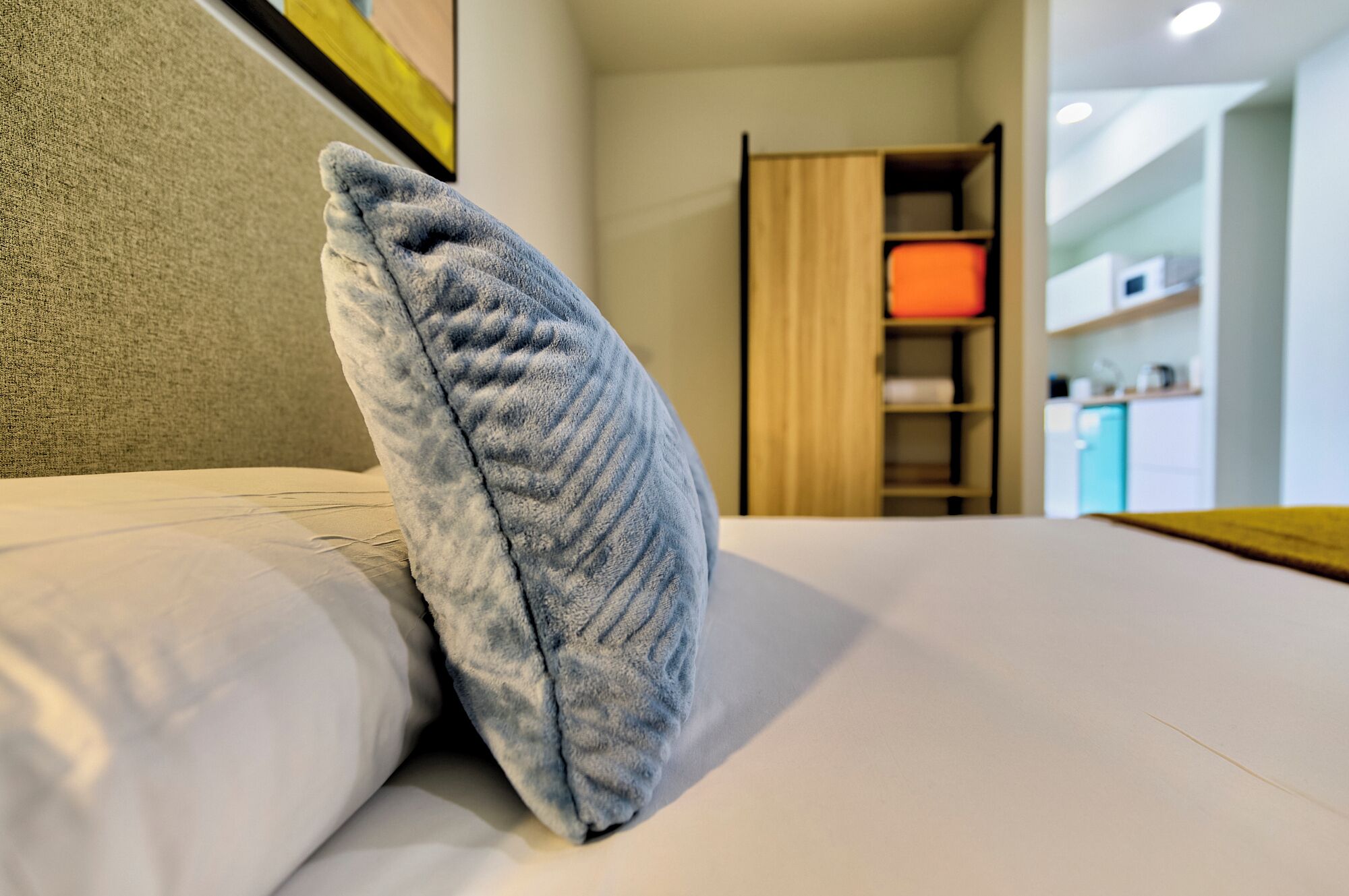 A neatly made bed with a single pillow and a neatly folded blanket.