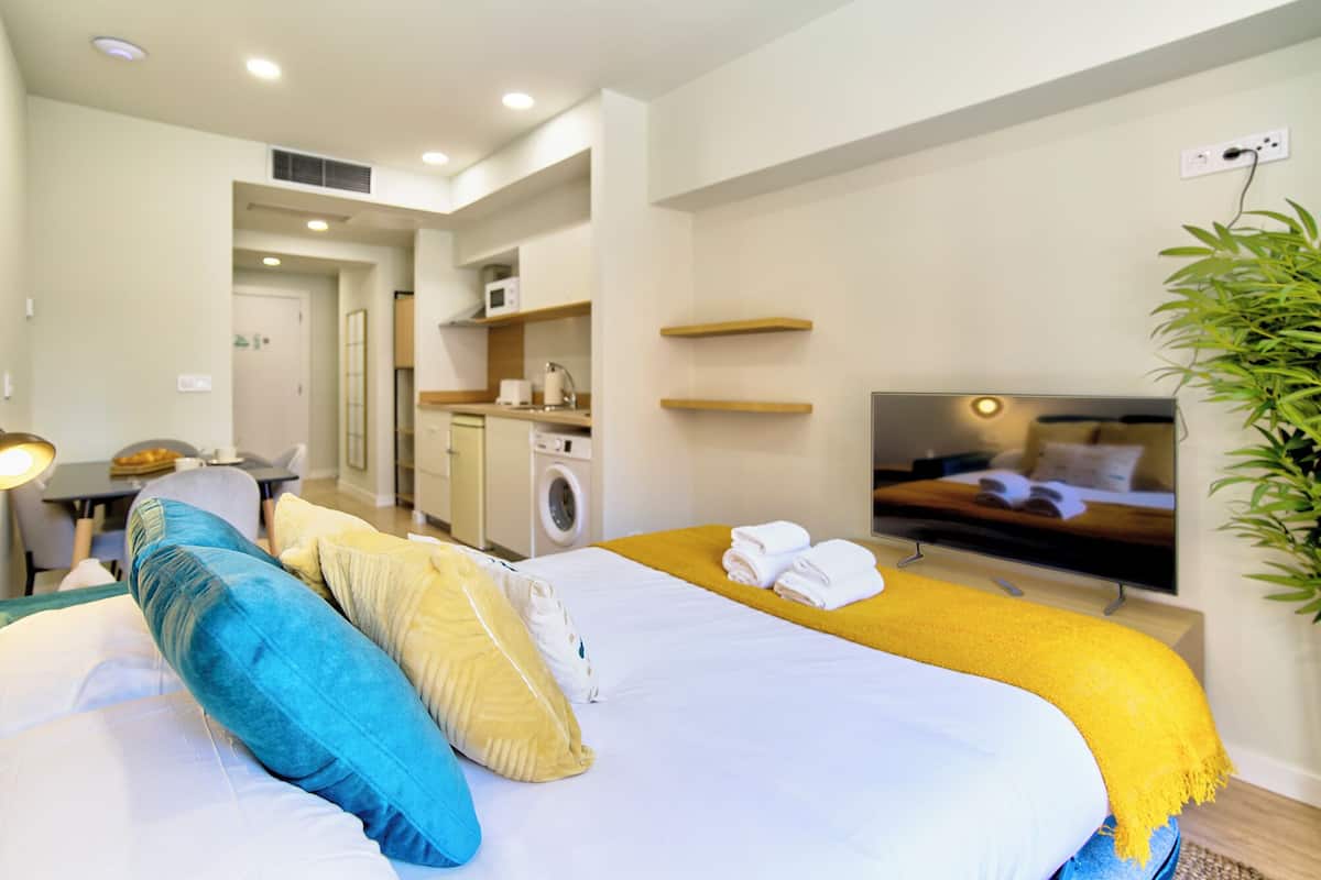 Une chambre d’hôtel moderne équipée d’un grand lit, d’une télévision, d’un lave-linge et d’un coin repas.