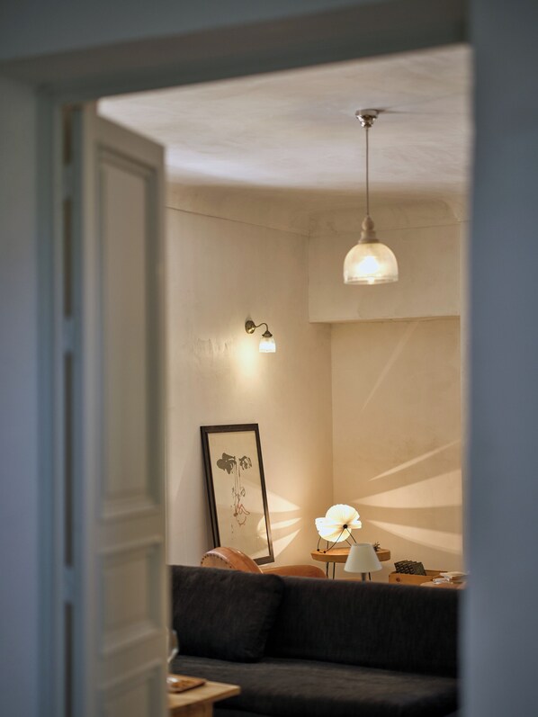 Une pièce chaleureuse avec un canapé aux couleurs sombres, une petite table avec une lampe et un tableau encadré au mur.